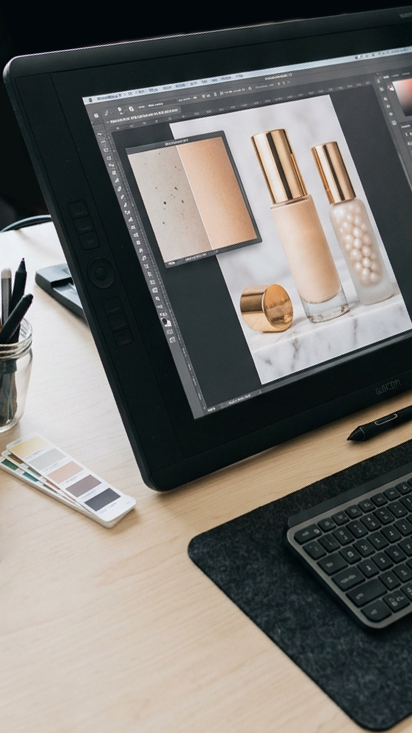 Professioneller Retusche-Arbeitsplatz mit Wacom Cintiq und schwarzer Logitech-Tastatur auf heller Tischplatte