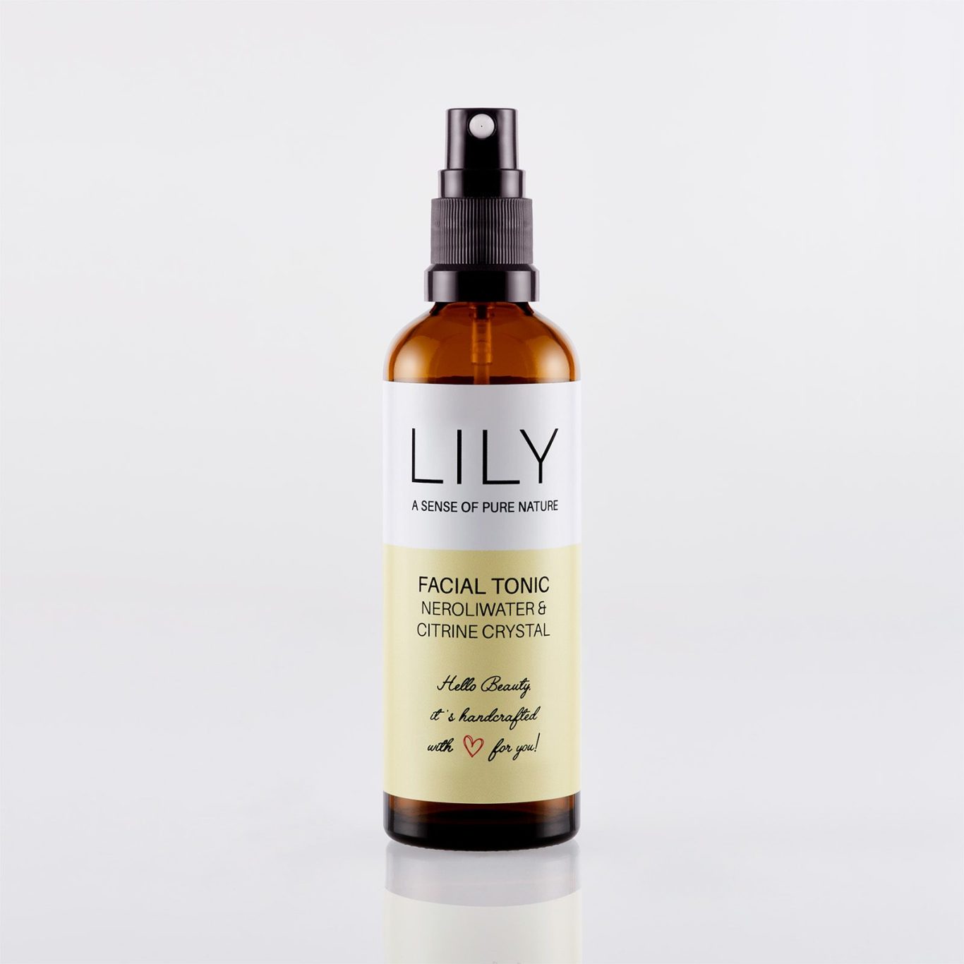 Freigestellte Braunglas-Sprühflasche für Naturkosmetik-Gesichtswasser mit schwarzem Zerstäuber und sanfter Bodenreflexion