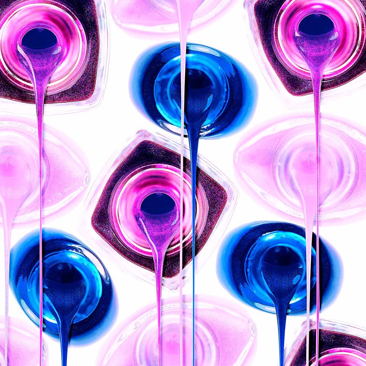 Kreative Beauty-Produktfotografie geöffneter Nagellack-Flakons in Violett, Blau und Rosé mit vertikal fließenden, glitzernden Farbfäden.