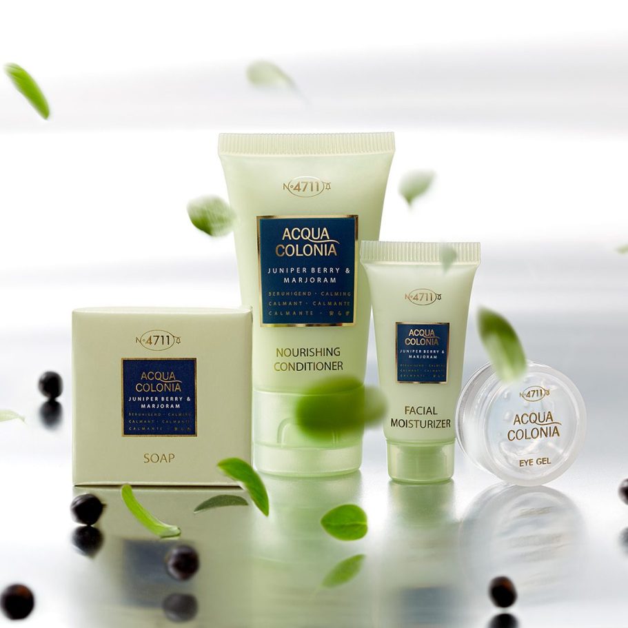 Atmosphärische Produktfotografie der Kosmetikserie 4711 Acqua Colonia mit schwebenden grünen Kräuterblättern und Wacholderbeeren.