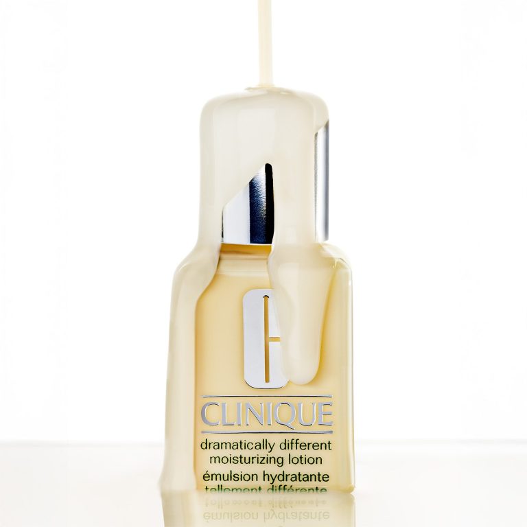 Kreative Kosmetik-Produktfotografie eines Pflege-Flakons (Clinique Moisturizing Lotion), überzogen von sanft fließender Creme-Textur.