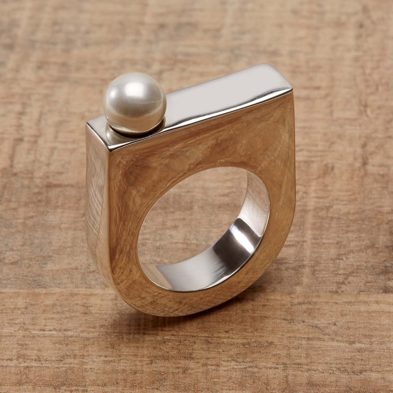 Außergewöhnlicher Design-Ring aus poliertem Silber mit schimmernder weißer Perle – Makro-Schmuckfotografie auf Naturuntergrund.